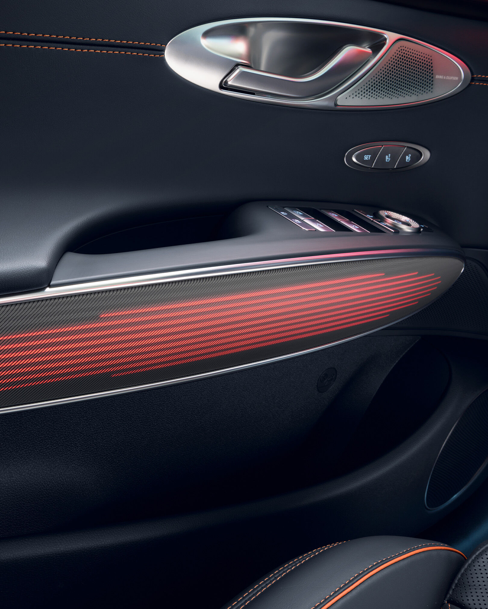 GV70 스포츠 패키지 차량 내부 문 손잡이의 붉은빛을 띄는 무드 조명이 보입니다. 그 위로는 문을 열 수 있는 손잡이와 다양한 제어 장치 버튼이 위치합니다.
