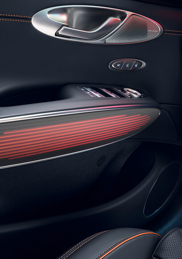 You can see the mood lighting in red on the interior door handle of the GV70 Sports Package. Above it are the door handle for opening and various control buttons.
