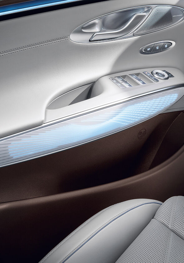 You can see the mood lighting in blue on the interior door handle of the GV70. Above it are the door handle for opening and various control buttons.