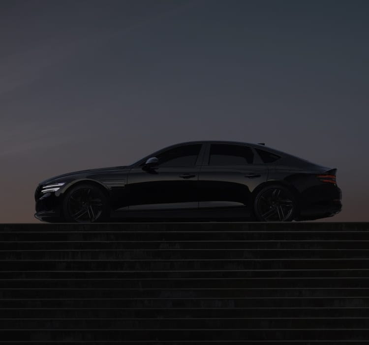 Genesis G80 luxury sedan in an elegant black finish, parked in front of a modern concrete backdrop.